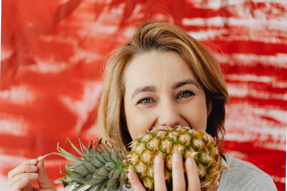 Person holding a golden pineapple up to the light, with a pleased smile